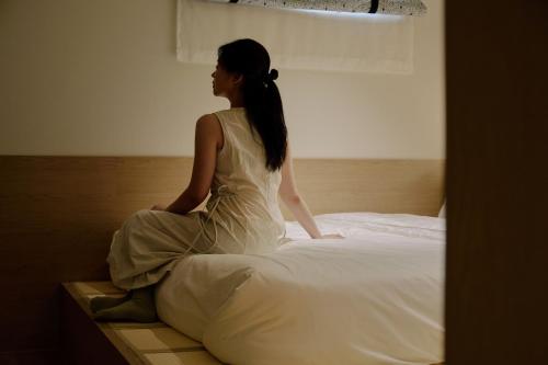 a woman sitting on top of a bed at Sowon Ryokan and Hotel by Aank Sangbong in Seoul