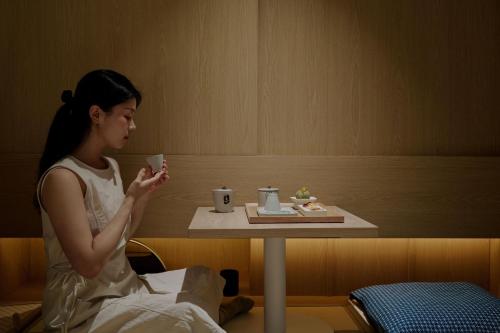 a woman sitting at a table with a cup of coffee at Sowon Ryokan and Hotel by Aank Sangbong in Seoul