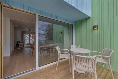 a room with tables and chairs and a green wall at Northern Lights Apartments Tromsø in Tromsø