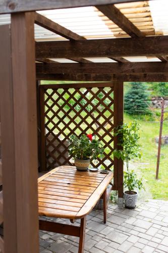 a wooden pergola with a wooden bench and two potted plants at Talsu Vecpilsētas apartmenti in Talsi