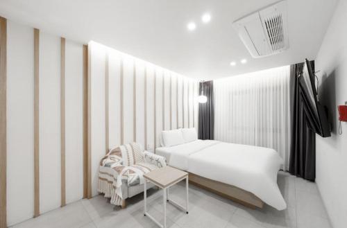 a bedroom with a white bed and a chair at Hotel Yaja Gwangju Mudeungsan branch in Gwangju