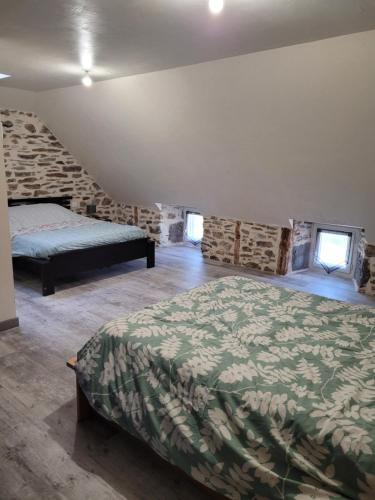 a bedroom with a bed and a stone wall at Maison à la campagne 4 à 9 personnes in Alleuze