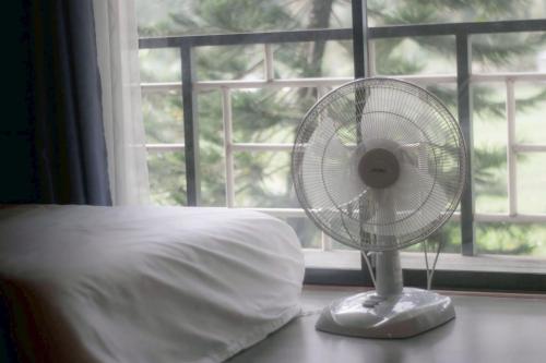 a white fan sitting on a table next to a bed at นานาเพชรบูรณ์ รีสอร์ท&คาเฟ่ 