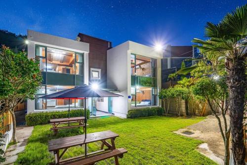 a house with a bench and an umbrella in the yard at Tongyeong Travel Guest Pension in Kwangsanch'on