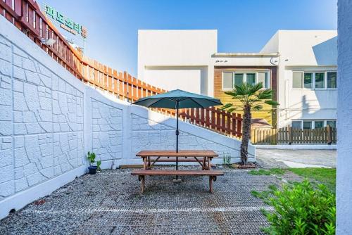 a picnic table with an umbrella next to a building at Tongyeong Travel Guest Pension in Kwangsanch'on