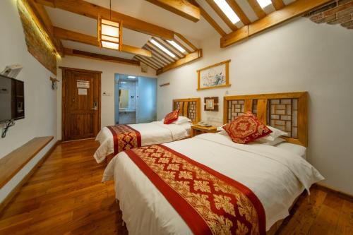 two beds in a room with wooden floors at Zhangjiajie Wangyi Inn in Zhangjiajie