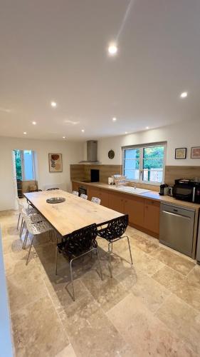 une grande cuisine avec une table et des chaises en bois dans l'établissement La grange du château Favor, à Bourg-de-Péage