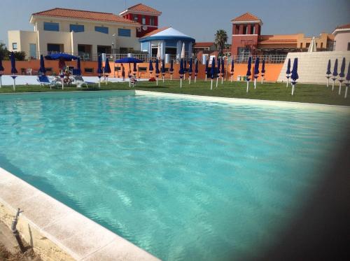 a large swimming pool with blue chairs and umbrellas at Le Torri in Santa Marinella