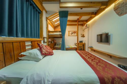 a bedroom with a large white bed and a television at Zhangjiajie Wangyi Inn in Zhangjiajie