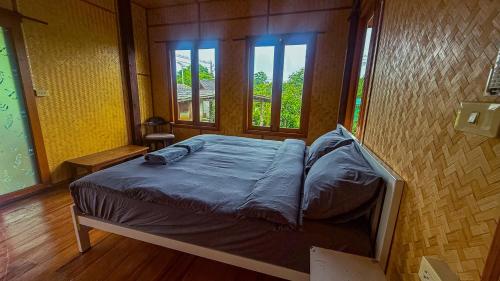 a small bed in a room with two windows at Nha-Da Land New Area in Chiang Dao