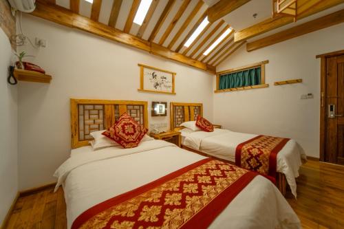 two beds in a room with wooden ceilings at Zhangjiajie Wangyi Inn in Zhangjiajie