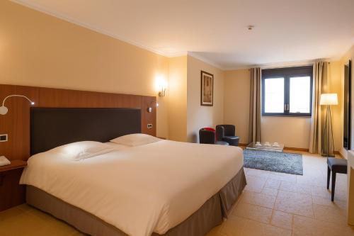 a bedroom with a large bed in a hotel room at Les Saules Parc & Spa - Teritoria in Vonnas