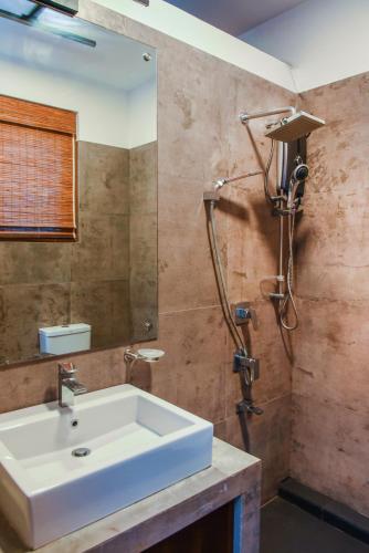 a bathroom with a white sink and a shower at Paradise Itzu in Kandy