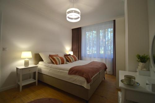 Un dormitorio con una cama grande y una ventana. en Apartamenty Marina na Wydmie, en Mrzeżyno