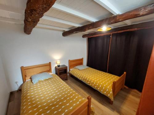 Dos camas en una habitación con una cortina negra. en Au petit hameau Cabrespine, en Cabrespine