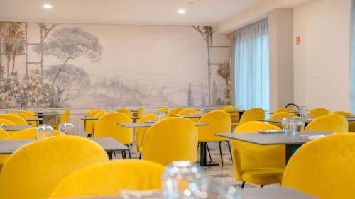 an empty dining room with yellow chairs and tables at AHG Riva Del Sole Hotel - Adults Only in Moniga