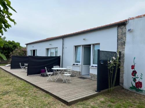 eine Terrasse mit einem Tisch und Stühlen sowie ein Gebäude in der Unterkunft LES TRÉMIÈRES N°1 - A 5MN DES PLAGES A VELO in La Michelière