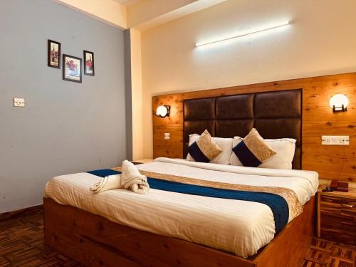 a bedroom with a large bed with a wooden headboard at Hotel Samiksha Manali in Manāli