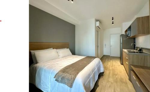 Un dormitorio con una cama grande y una cocina. en Campo Belo Brand New Studio, en São Paulo
