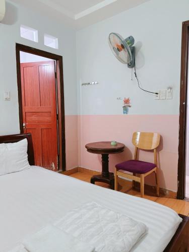 a bedroom with a bed and a table and a fan at Khách Sạn Bảo Long in Ho Chi Minh City