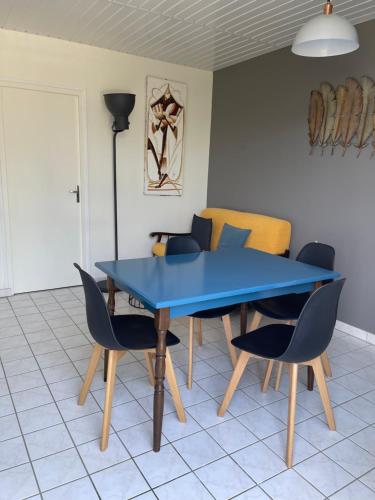 einen blauen Tisch und Stühle im Wohnzimmer in der Unterkunft LES TRÉMIÈRES N°1 - A 5MN DES PLAGES A VELO in La Michelière
