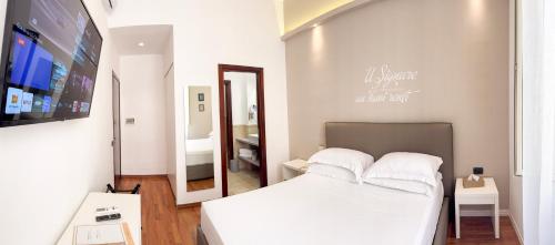 a bedroom with a white bed and a mirror at BADIA NUOVA Apart Hotel in Trapani