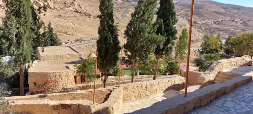 a stone wall with trees and a road at Hayat Zaman Hotel And Resort Petra in Wadi Musa