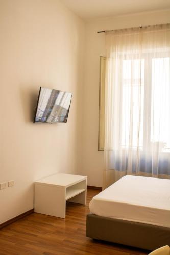 a bedroom with two beds and a tv on the wall at BADIA NUOVA Apart Hotel in Trapani