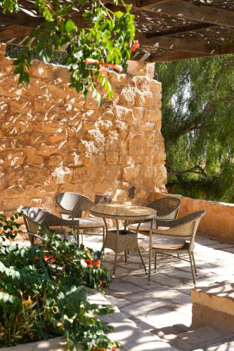 a patio with a table and chairs and a stone wall at Hayat Zaman Hotel And Resort Petra in Wadi Musa