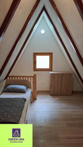 a attic room with a bed and a window at Green Una Wooden House in Kulen Vakuf
