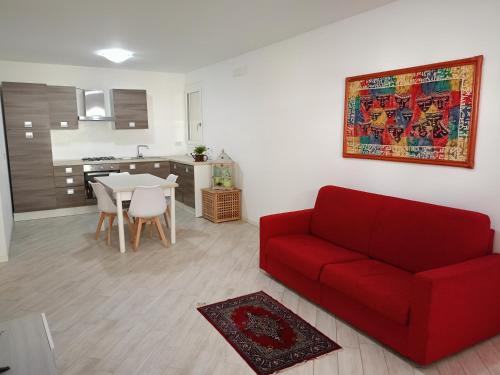a living room with a red couch and a kitchen at Corte Don Bosco 2 in Monfalcone