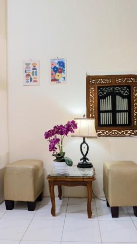 a room with a table with a lamp and purple flowers at Surabaya Homey Dharmahusada Syariah in Surabaya