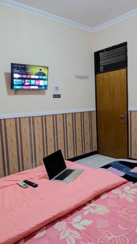 a laptop computer sitting on top of a bed at Surabaya Homey Dharmahusada Syariah in Surabaya