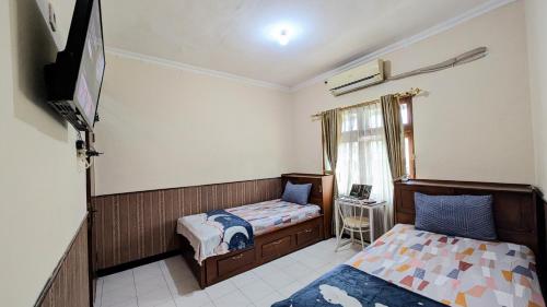 a bedroom with two beds and a tv in it at Surabaya Homey Dharmahusada Syariah in Surabaya