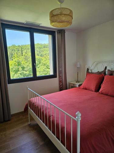 a bedroom with a bed with red pillows and a large window at Maison individuelle plein centre avec jardin ,au pied du Mont Ventoux in Malaucène