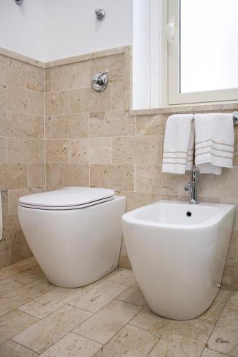 a bathroom with a white toilet and a sink at BADIA NUOVA Apart Hotel in Trapani