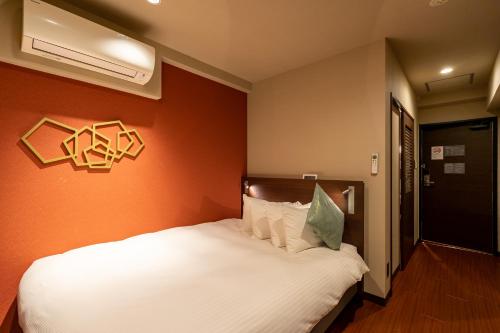a bedroom with a white bed with an orange wall at Red Roof Inn Kamata / Haneda Tokyo in Tokyo