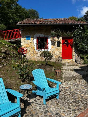 two blue chairs sitting in front of a house with a red door at Hotel Boutique Santuario Kunturi - Adults Only in Llanes