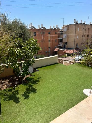 a yard with green grass and buildings in the background at יחידת אירוח גלילי in Qiryat Shemona