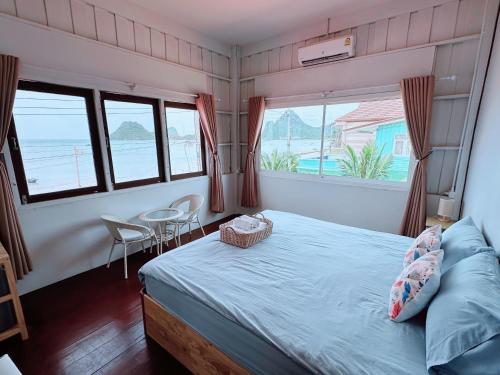 a bedroom with a bed and two windows and a table at Hostel 126 Cafe' & Bar in Prachuap Khiri Khan