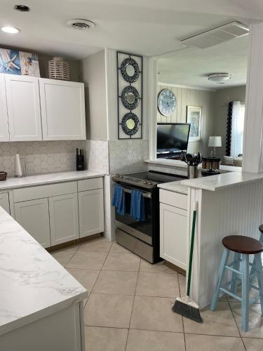 a kitchen with white cabinets and a stove top oven at Great Shape After Milton-pool Home Wows! Po in Venice