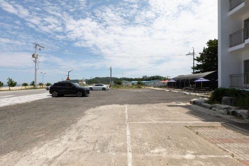 Un coche aparcado en un aparcamiento junto a un edificio. en Olive Beach Pension, en Yangyang
