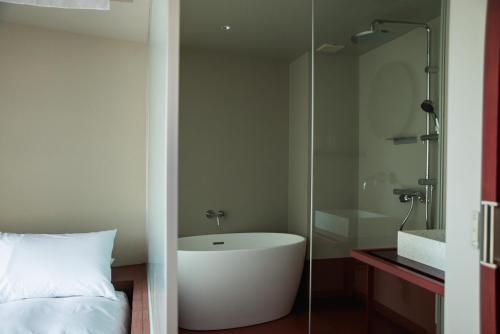 a bathroom with a bath tub and a bed at SOIL Nihonbashi Hotel in Tokyo