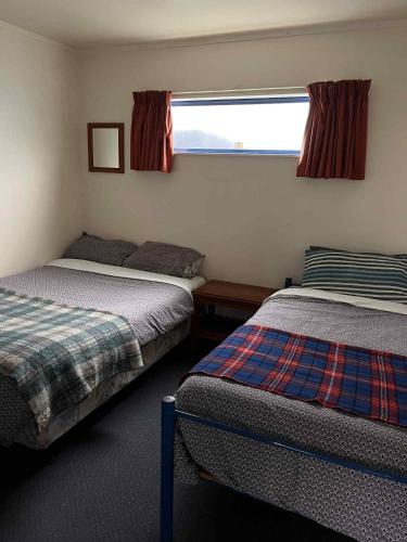 a bedroom with two beds and a window at Tongariro River Retreat in Turangi