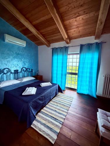a bedroom with blue curtains and a bed with a rug at Agriturismo Corte Sakura in Montefiascone