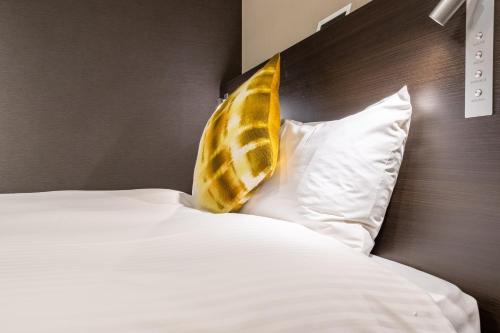 a bed with a yellow and white pillow on it at Red Roof Inn Kamata / Haneda Tokyo in Tokyo