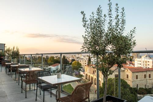 a balcony with tables and chairs and a view of the city at Rise Urban Art Hotel in Larnaka