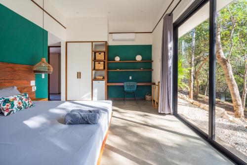 a bedroom with a bed and a large window at Rancho Coco Boutique Hotel Playa Negra in Río Sequito