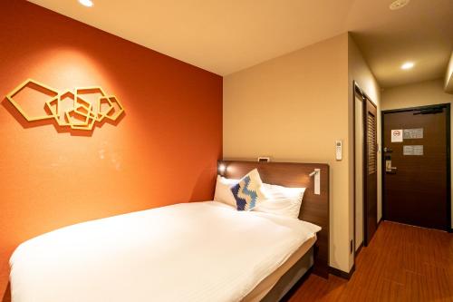 a bedroom with a white bed with an orange wall at Red Roof Inn Kamata / Haneda Tokyo in Tokyo