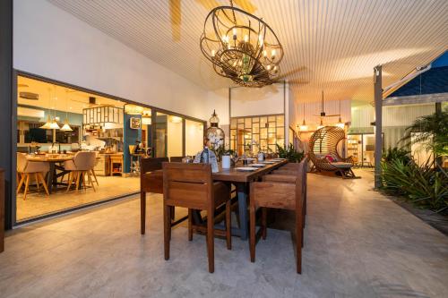 a dining room with a table and chairs and a chandelier at Contemporary Eden - Villa Jeladore, 5BR, Garden & Pool, near Laguna in Bang Tao Beach